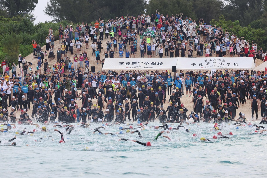 2一斉に海に入り、スタートする大勢の選手たち=20日午前7時、宮古島市与那覇前浜ビーチ